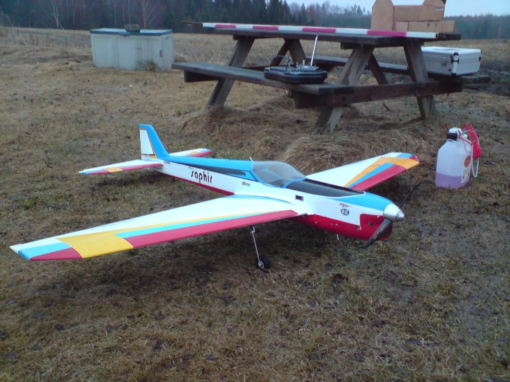 a toy plane sitting on the ground near picnic tables