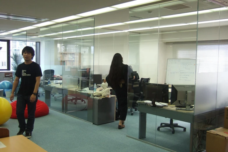 two people walking past the computers on glass walls