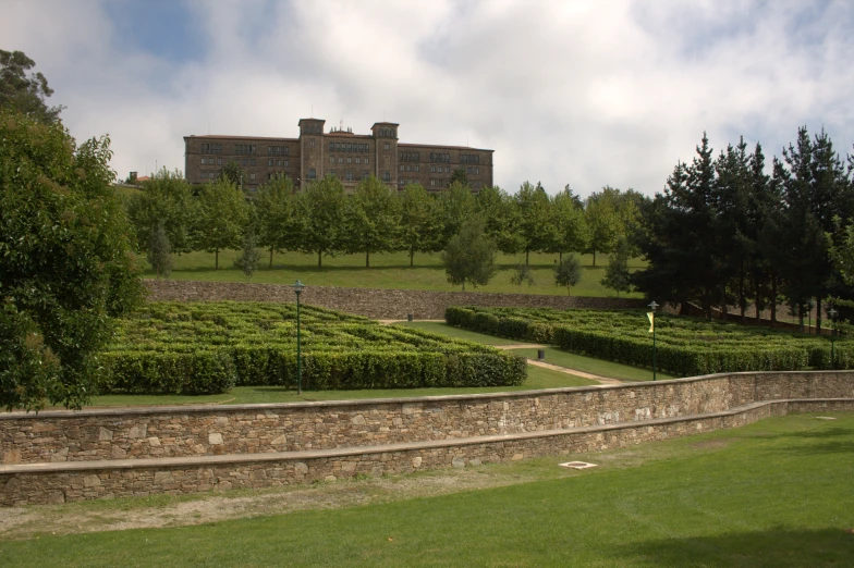 a stone wall near trees and an expansive building