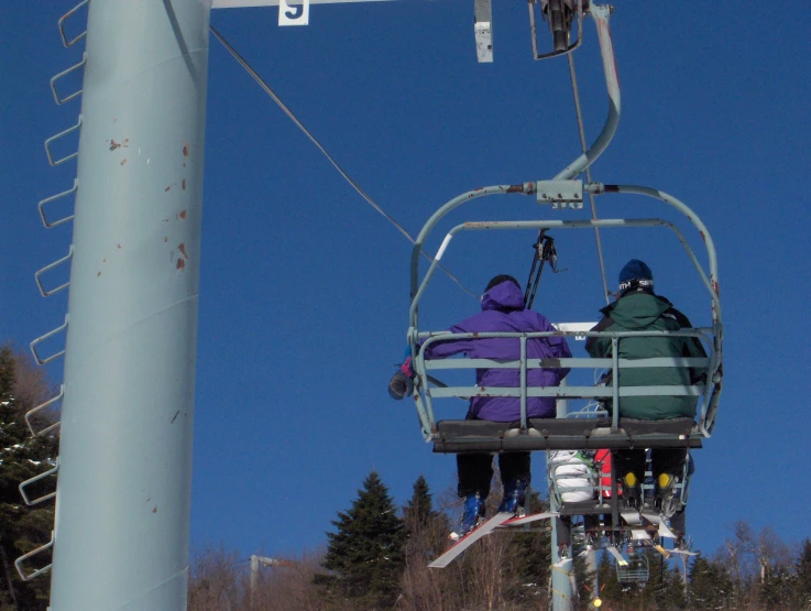 two skiers ride the lift during the day