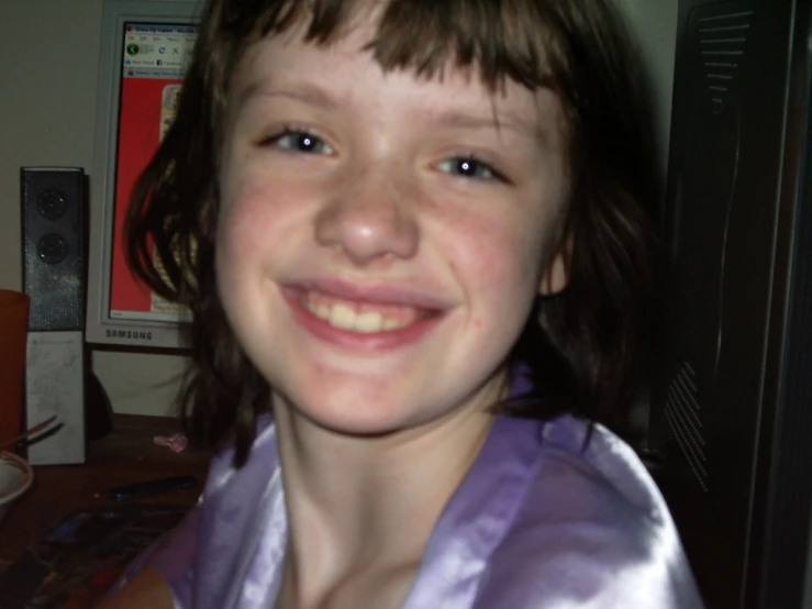 a smiling  with dark hair wearing a purple robe