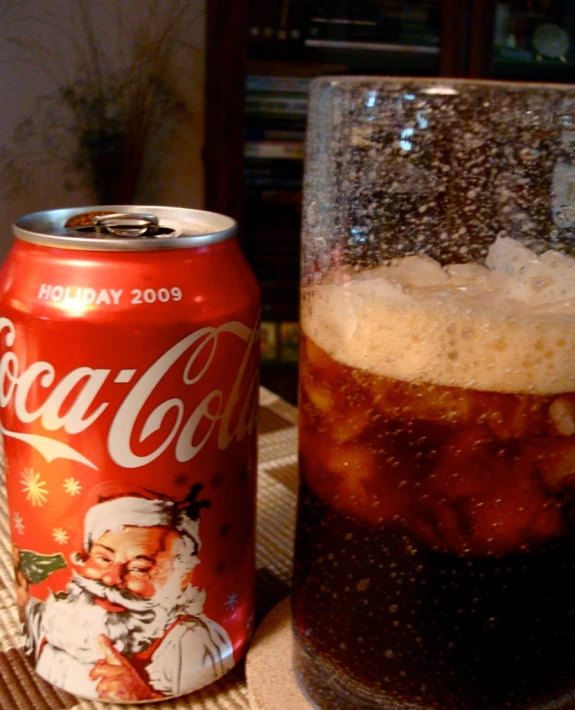a can with cola and a drink on a table