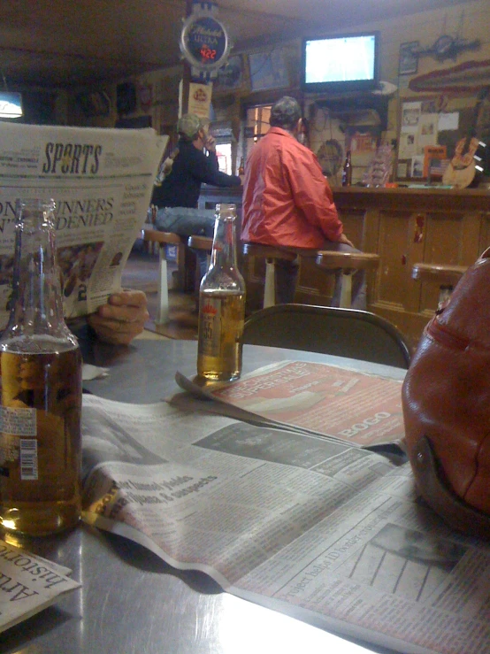 a close up of a newspaper on a table with bottles of beer