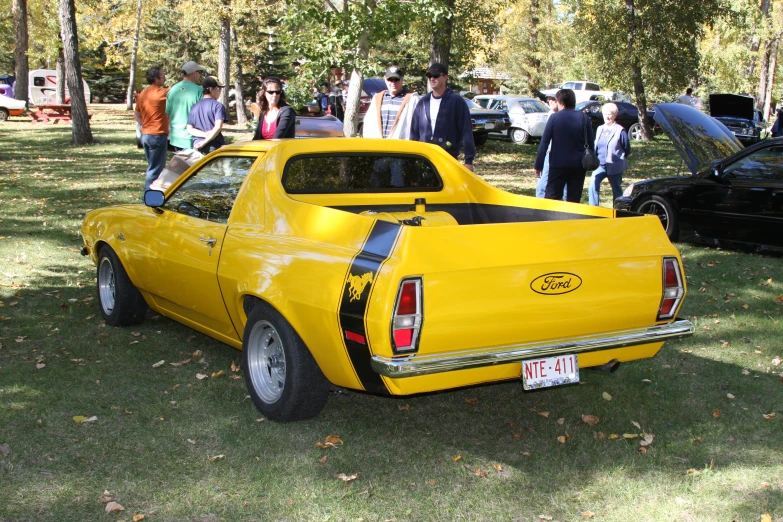 a yellow pickup truck at an event parked near other cars