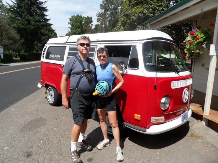 two people stand next to a red and white vw van