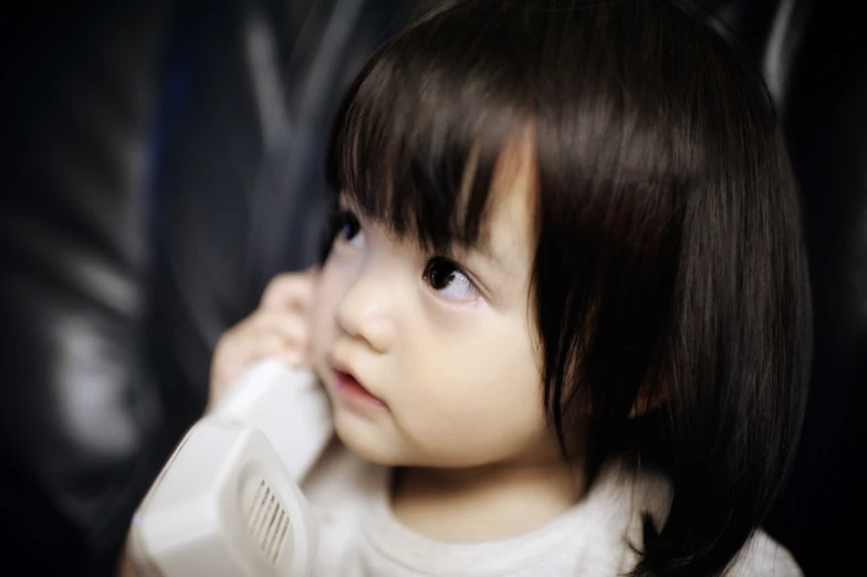 a child holds a telephone up to her ear
