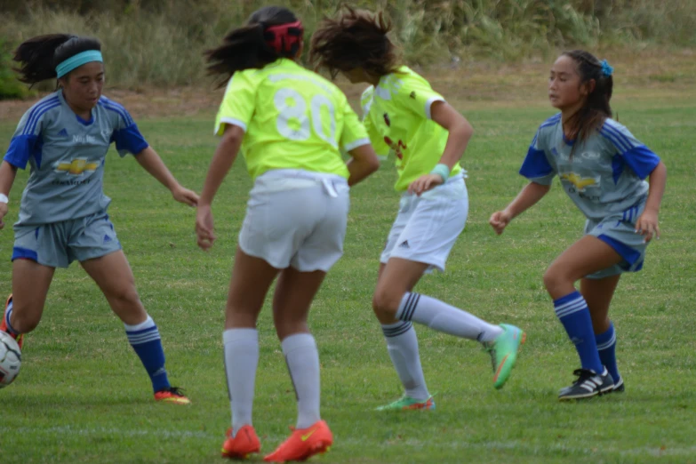 group of women playing soccer on field of grass