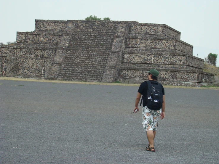 there is a man walking next to an ancient structure