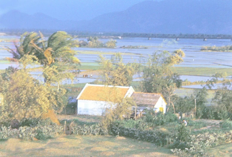 a small house sits in the middle of some land next to a lake