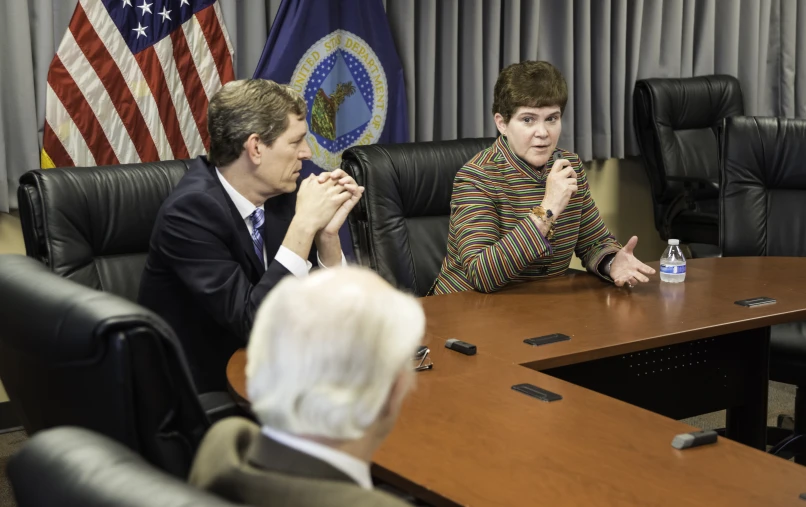 two people sitting in chairs near an american flag