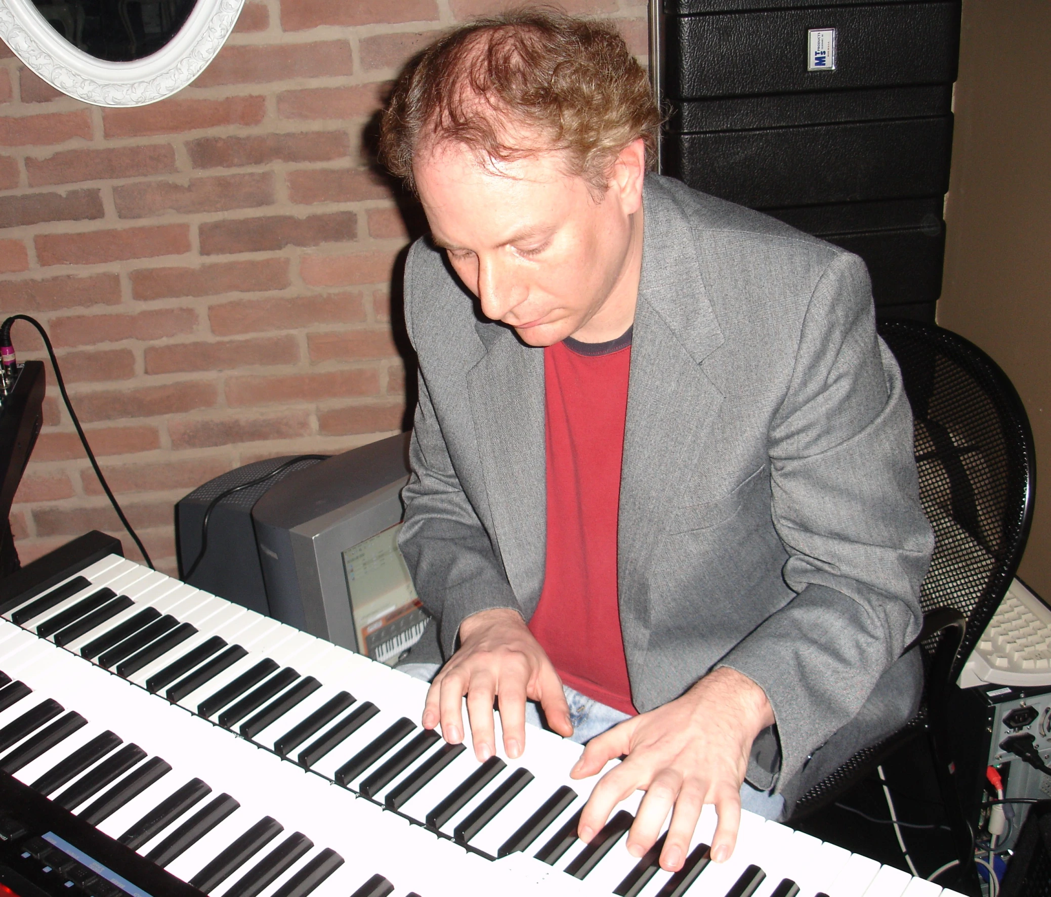 the man is playing on a keyboard next to a brick wall