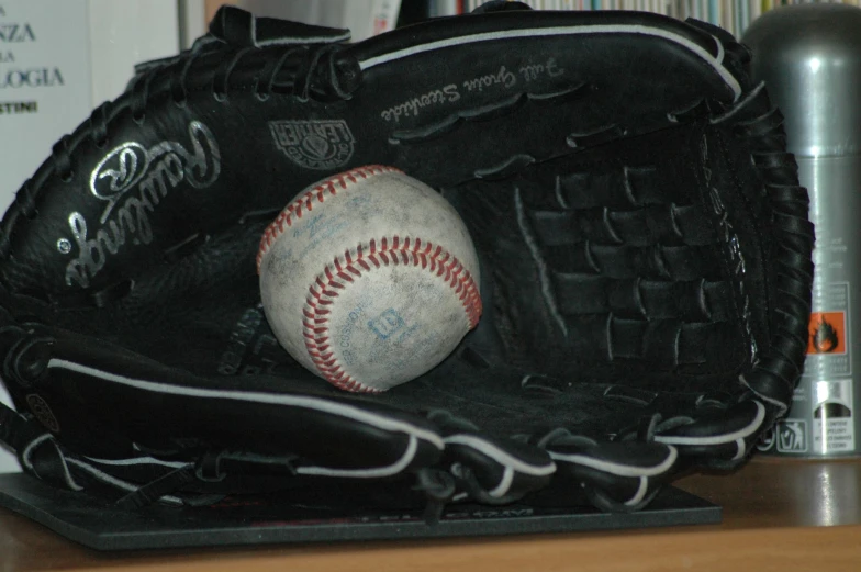 an autographed raw baseball in a black catchers mitt