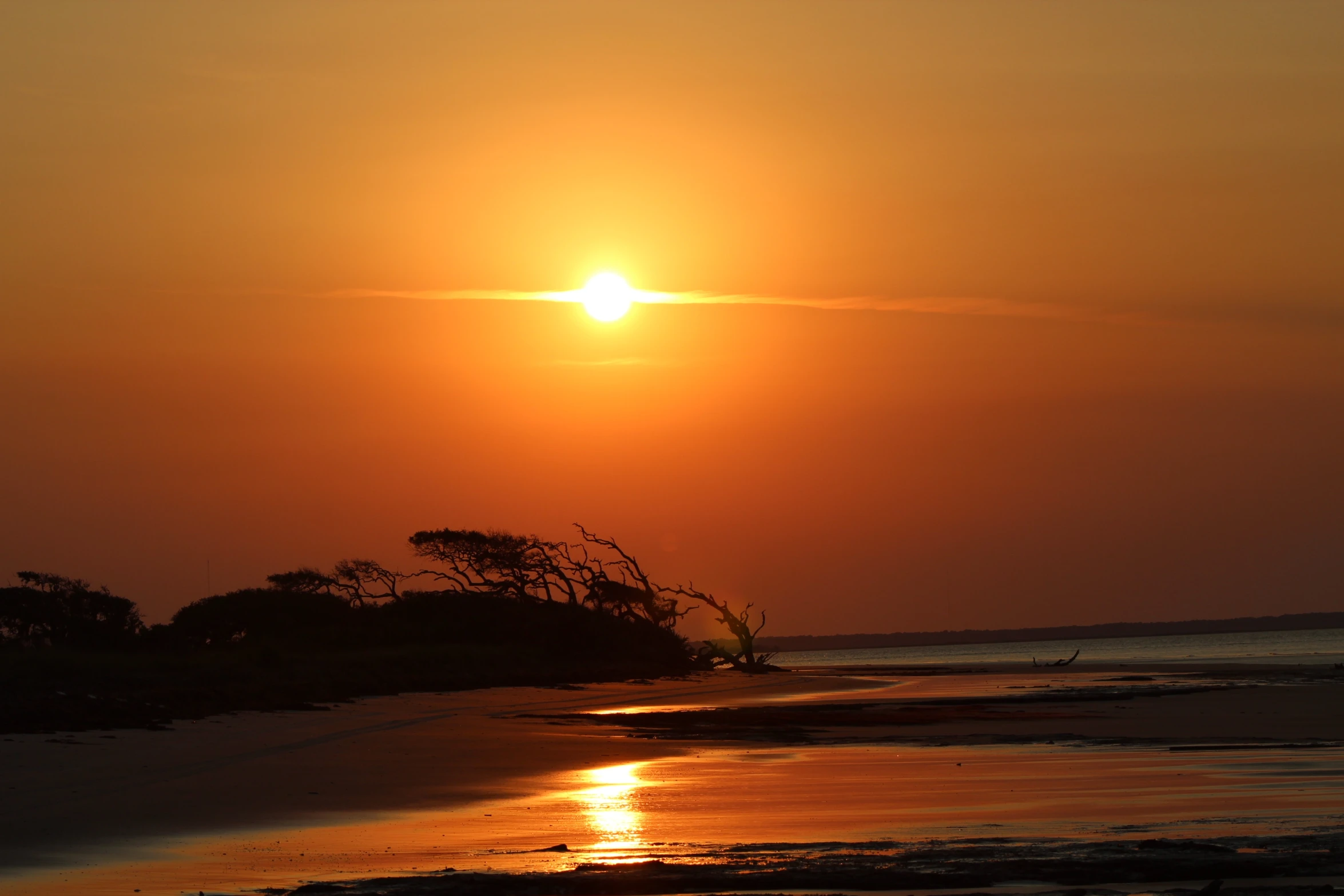 a bright sun sets over the horizon of the beach