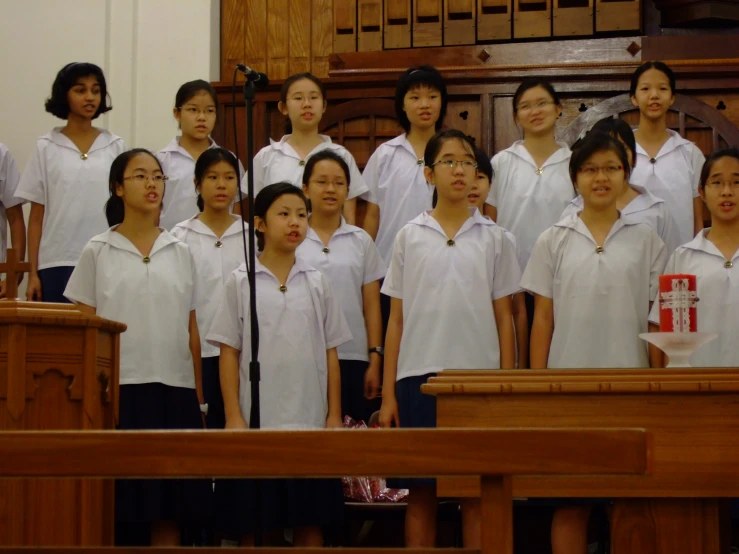 a choir singing in front of a microphone with white shirts on