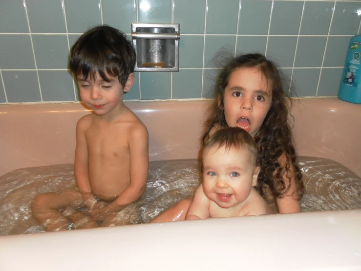 three children sitting in a bathtub with no one on them