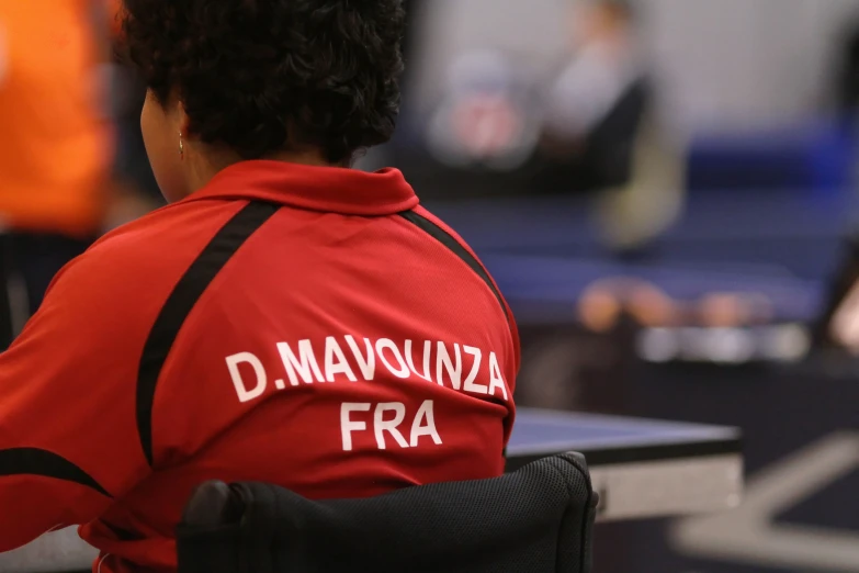 a boy in red shirt sitting at table with a bag