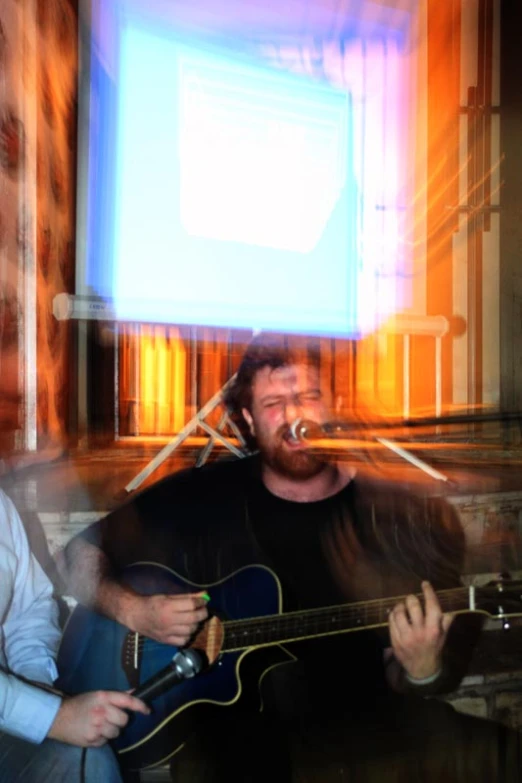 a man is sitting with his guitar and smiling