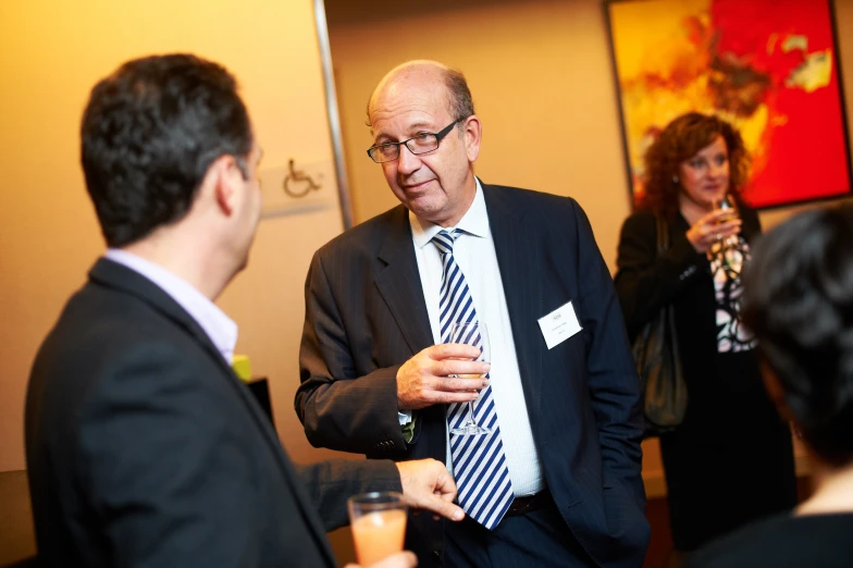 two men in suits talking to some other people