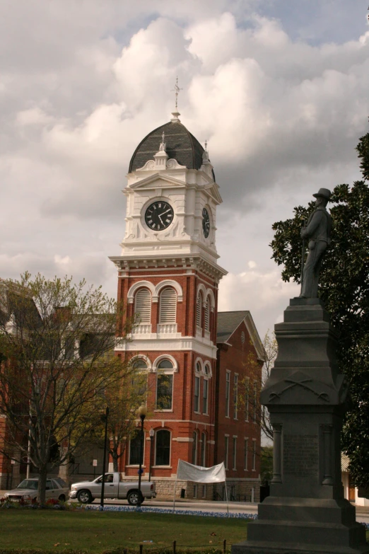 a large clock tower with a statue on a corner in the foreground