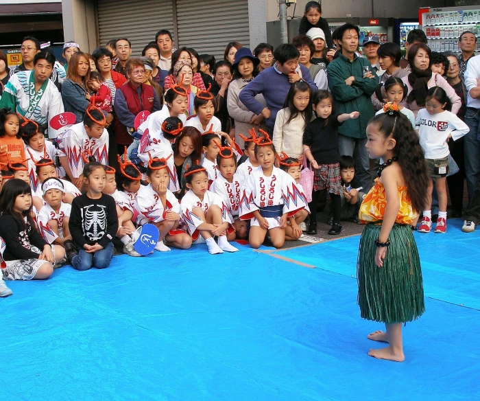 several children are watching an older man perform on stage