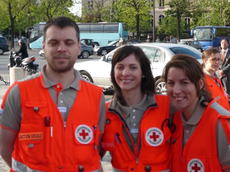 three people in orange safety vests on a busy street