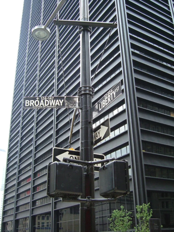 traffic signal and street sign on a lamp post in front of a very high - rise building