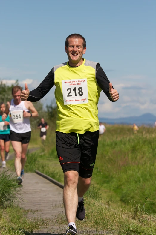 man running down a path while showing thumb up sign