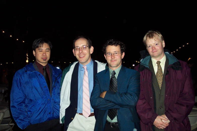 three young men standing side by side wearing suits