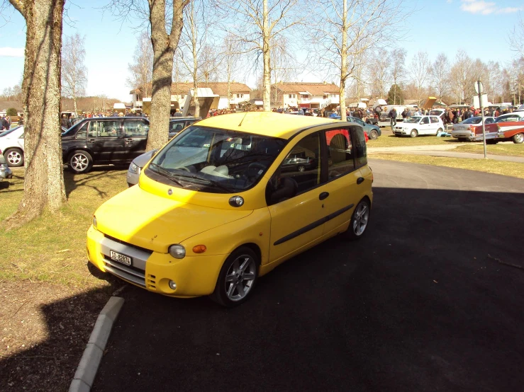 a yellow car sits in the street in a parking lot