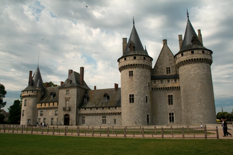 a castle style building with a tower next to the fence