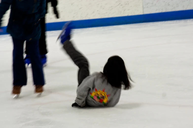 a girl is falling off of her skateboard at a skating rink