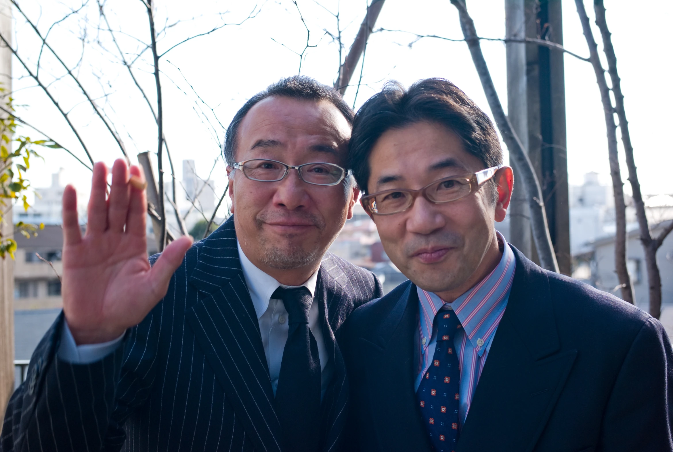 two asian businessmen are standing and giving a gesture