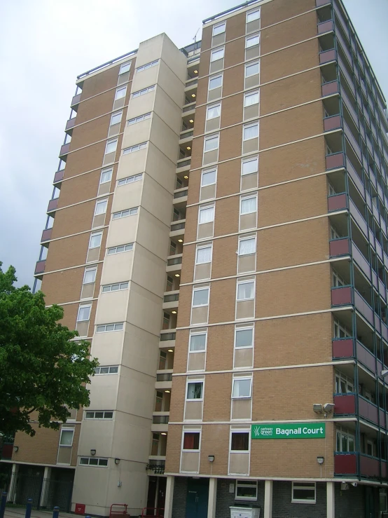 a big tan building with multiple windows and street signs in front