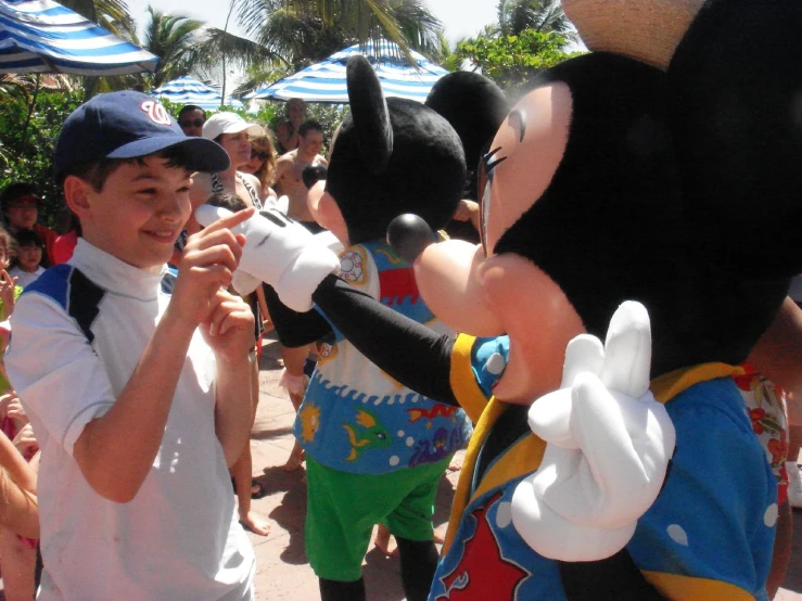 a boy smiles at an mickey mouse mascot