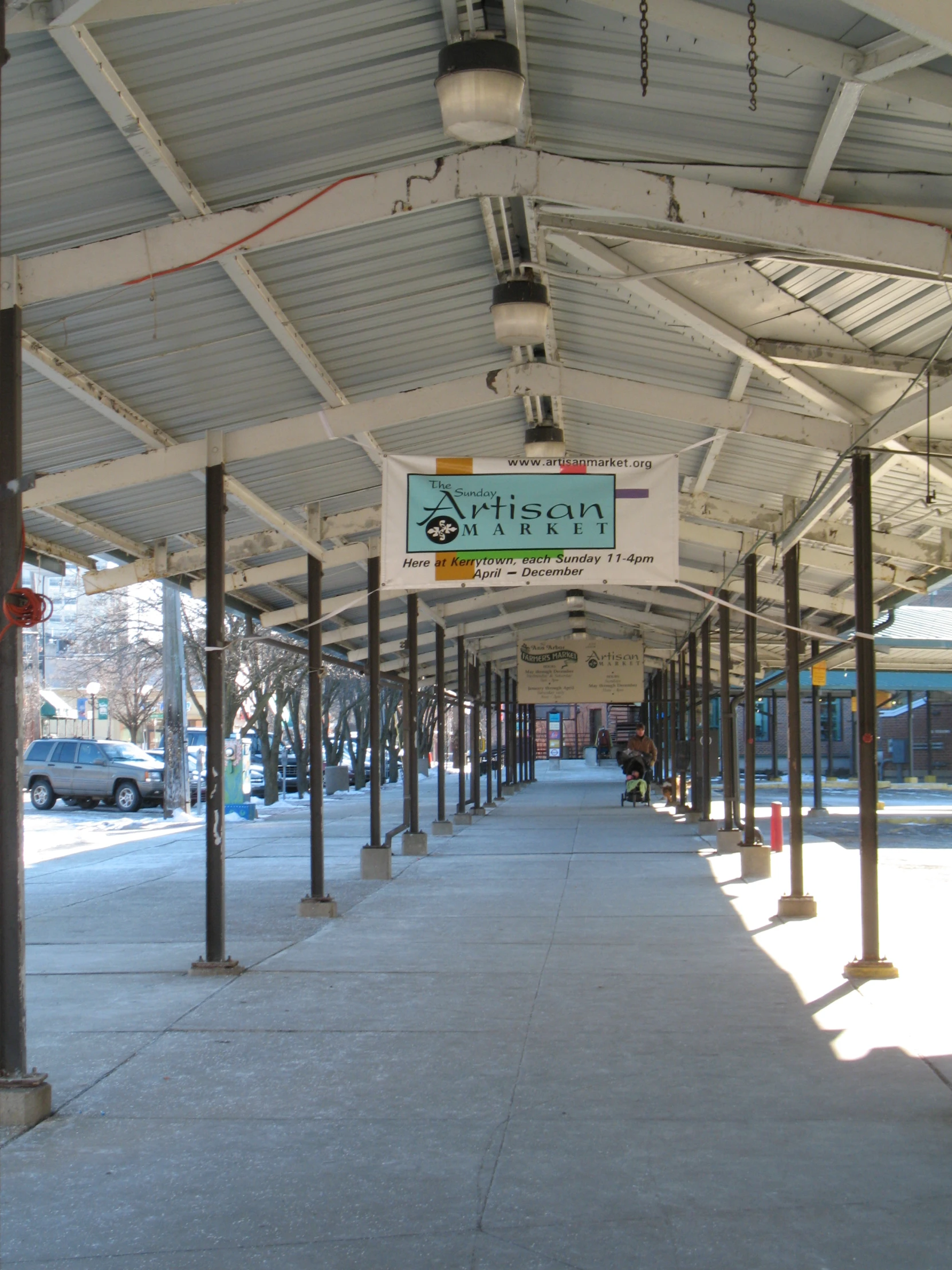 a covered walkway with parking meters and signs on it