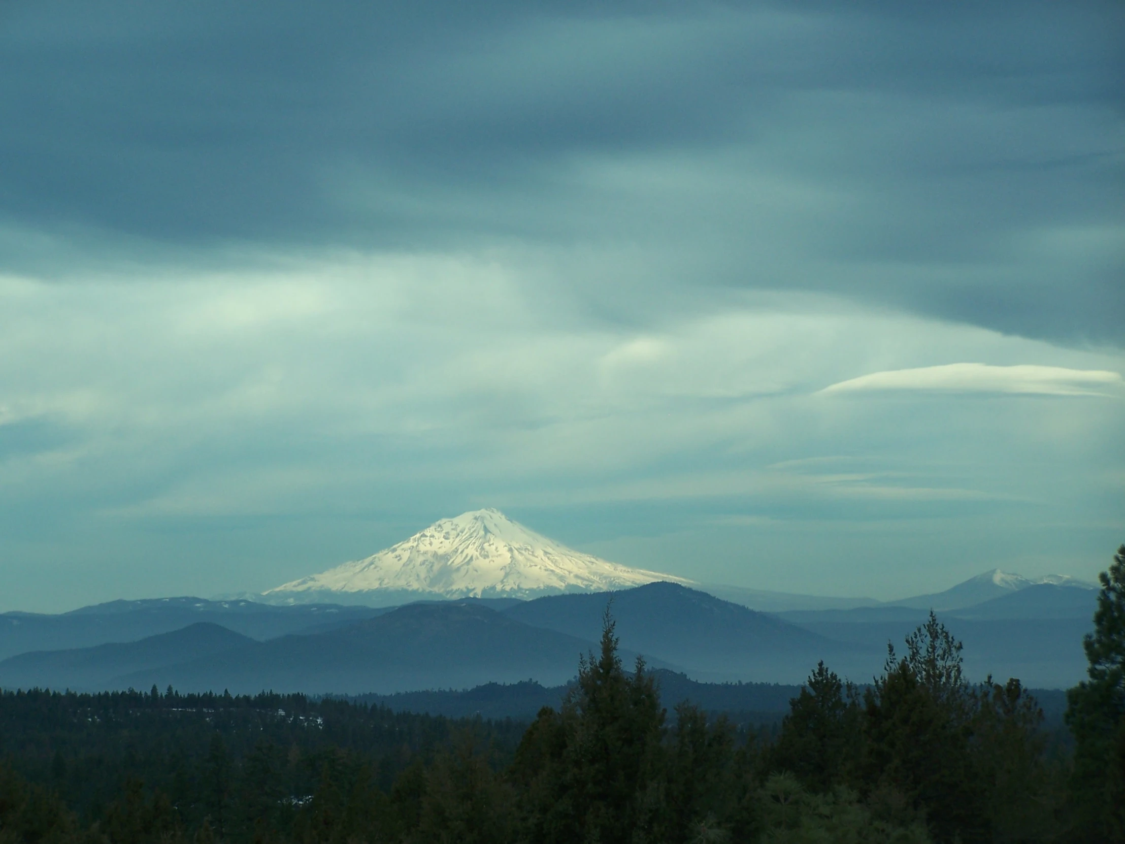 the snow covered mountain in the distance on a cloudy day