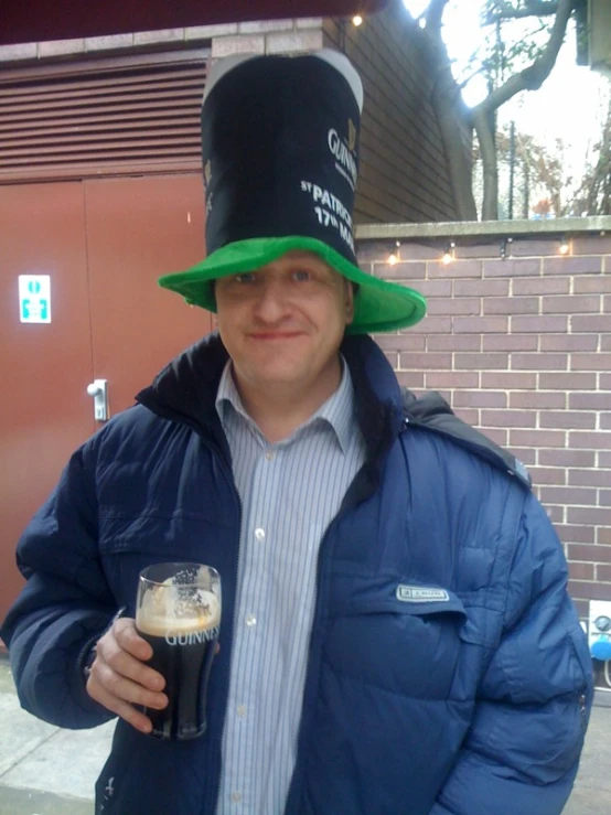 a man holding a pint and drink wears a hat