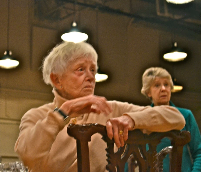 two older people are sitting at a table and one has a cell phone in his hand