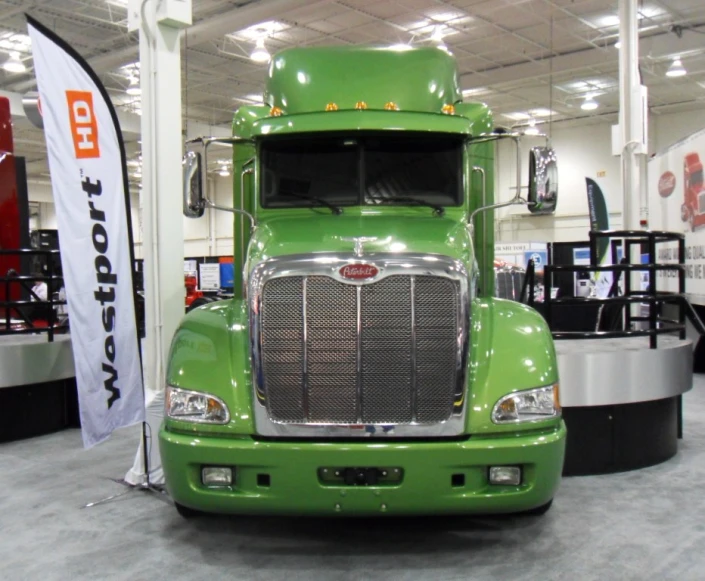 a green tractor trailer sits in an exhibit hall