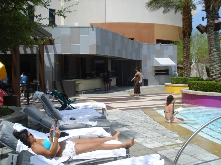 people relaxing on beach chairs near a swimming pool