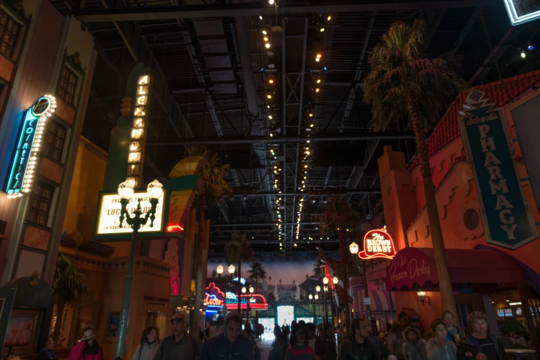 people are walking along a street with lights in the ceiling