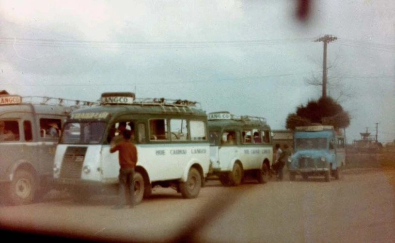 some men are standing next to many old trucks