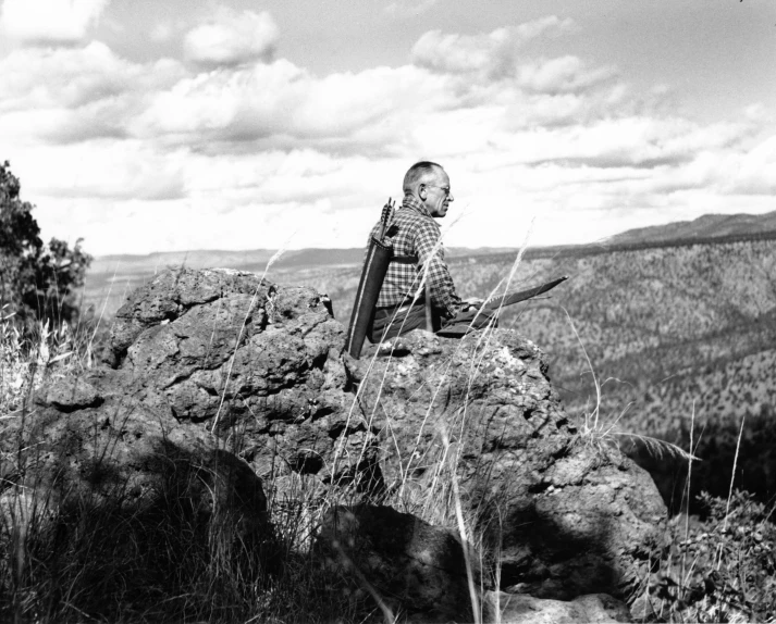 a black and white pograph of a boy on top of a rock