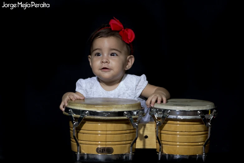 a small child sits in front of three drums