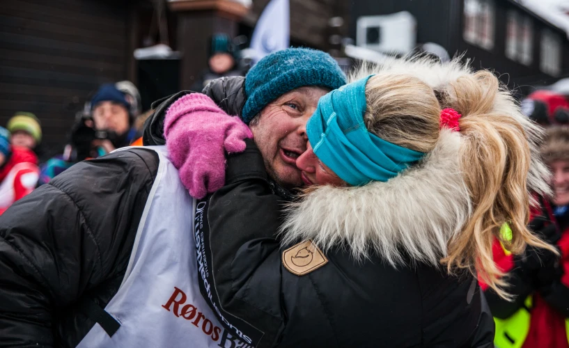 people wearing skis and warm clothing hug and hug