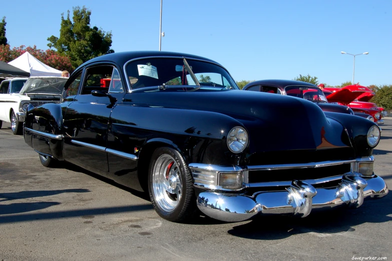 a classic car in the parking lot with other cars behind it