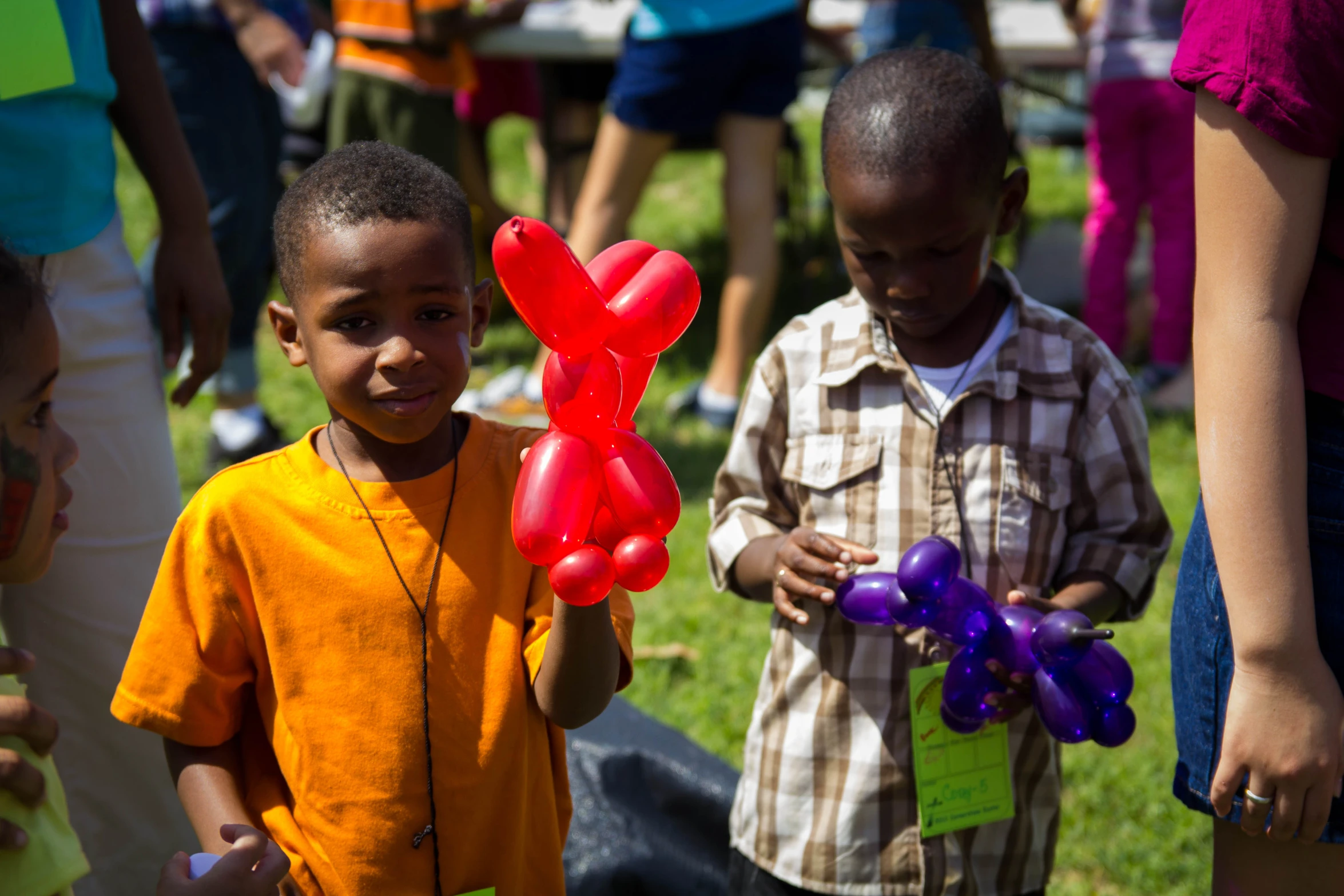 two boys hold balloon shaped kites with a bow on their head