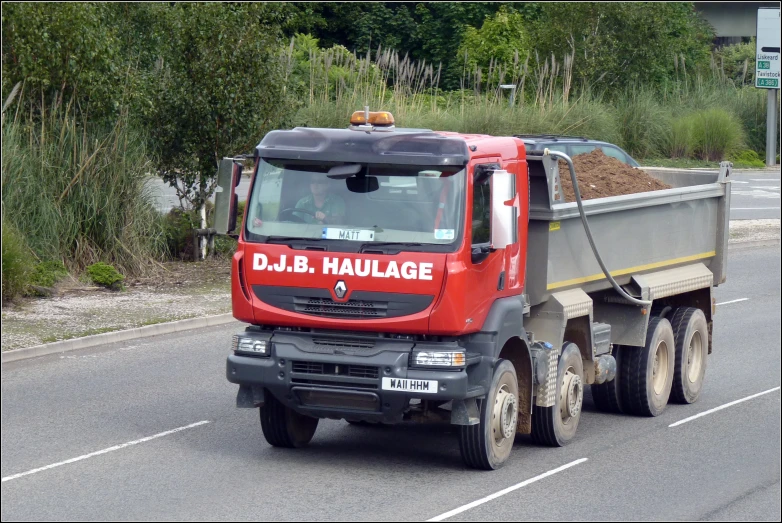 a dump truck driving down the road with a pile of dirt