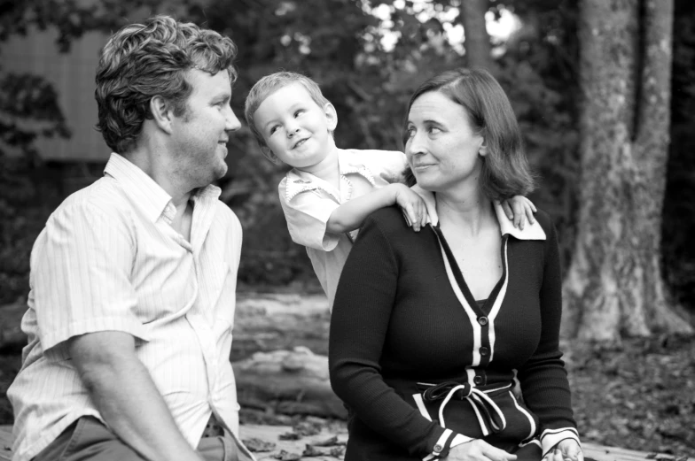 a young child is sitting on the lap of a woman and a man who are talking