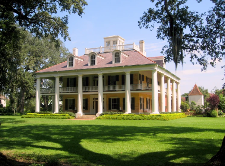 a large white and tan house sitting in a park